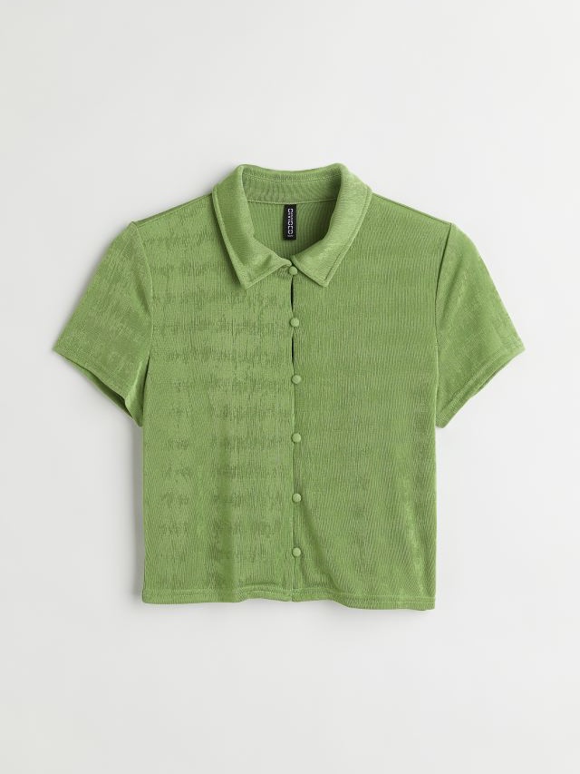 A short-sleeved sage green button-up shirt.