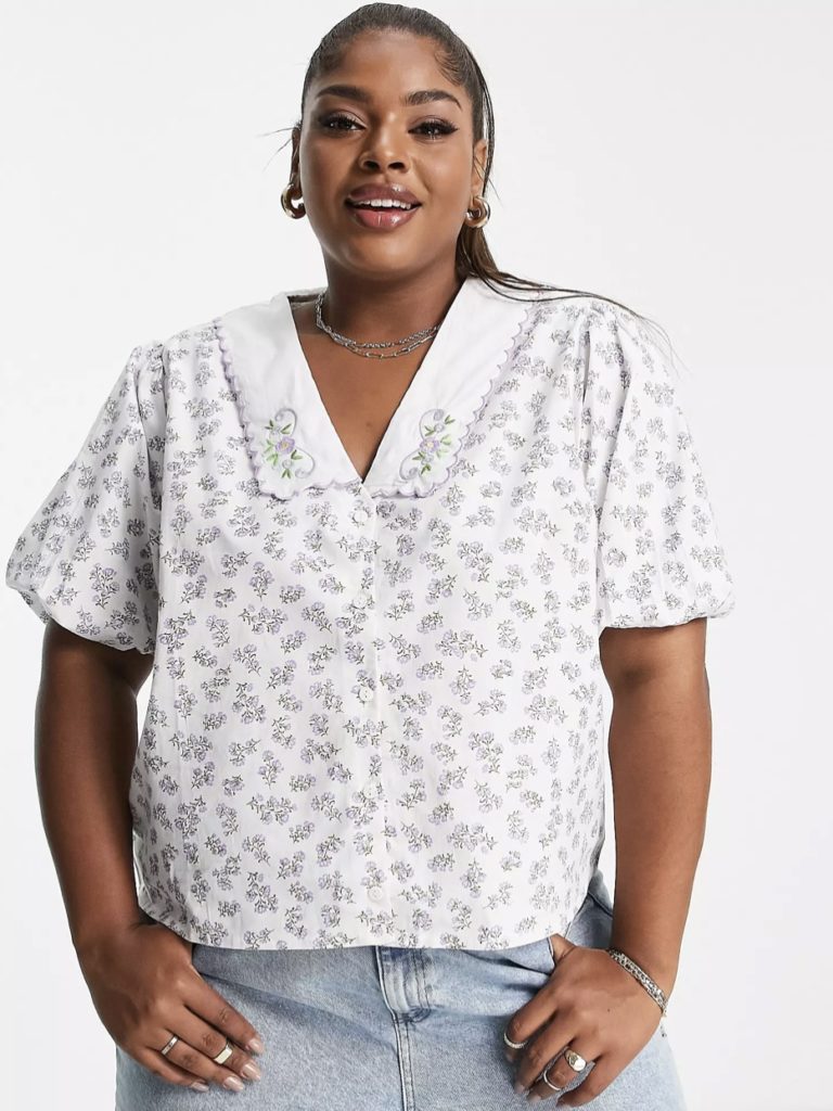 A white plus-size patterned relaxed short-sleeved blouse.