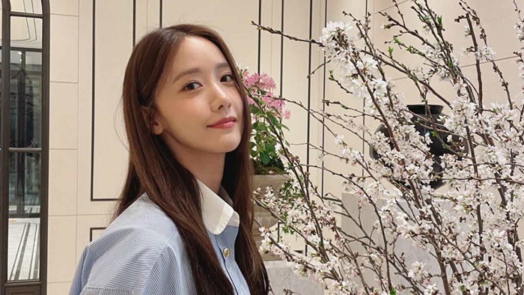 YoonA posing next to branches of white flowers.