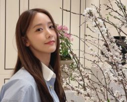 YoonA posing next to branches of white flowers.